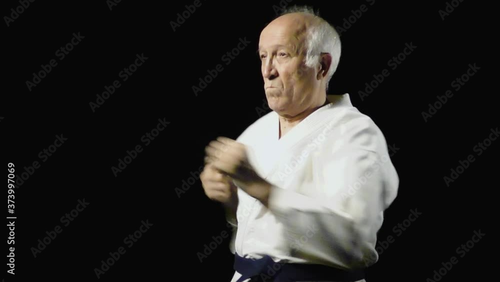 Punches and blocks with hands are trained by an old man athlete with a blue belt Punches and blocks with hands are trained by an old man athlete with a blue belt