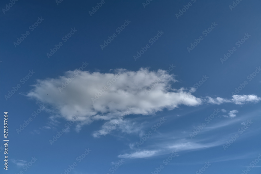 Lonely white cumulus cloud in a blue spring sky. Nature background.