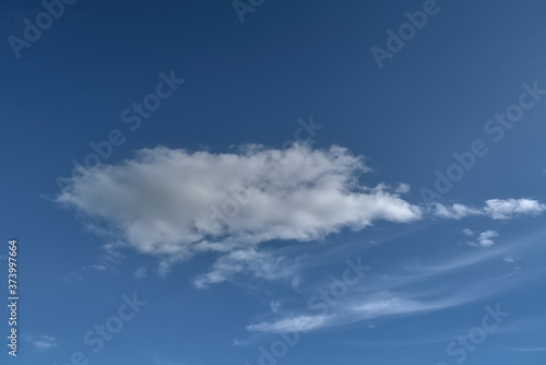 Lonely white cumulus cloud in a blue spring sky. Nature background.