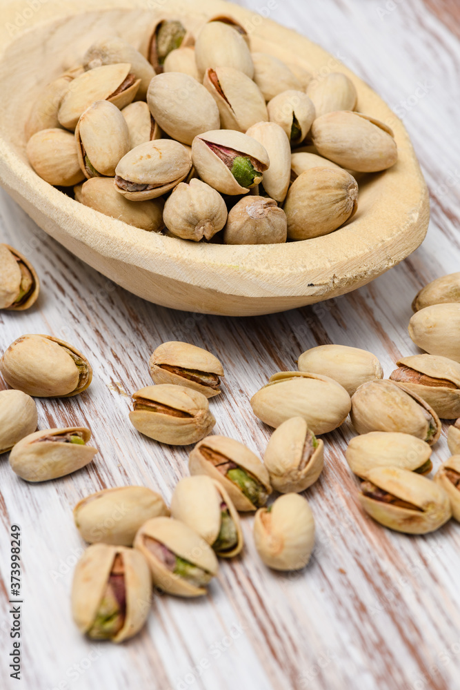 Pistachio nuts in wood spoon on wood background.