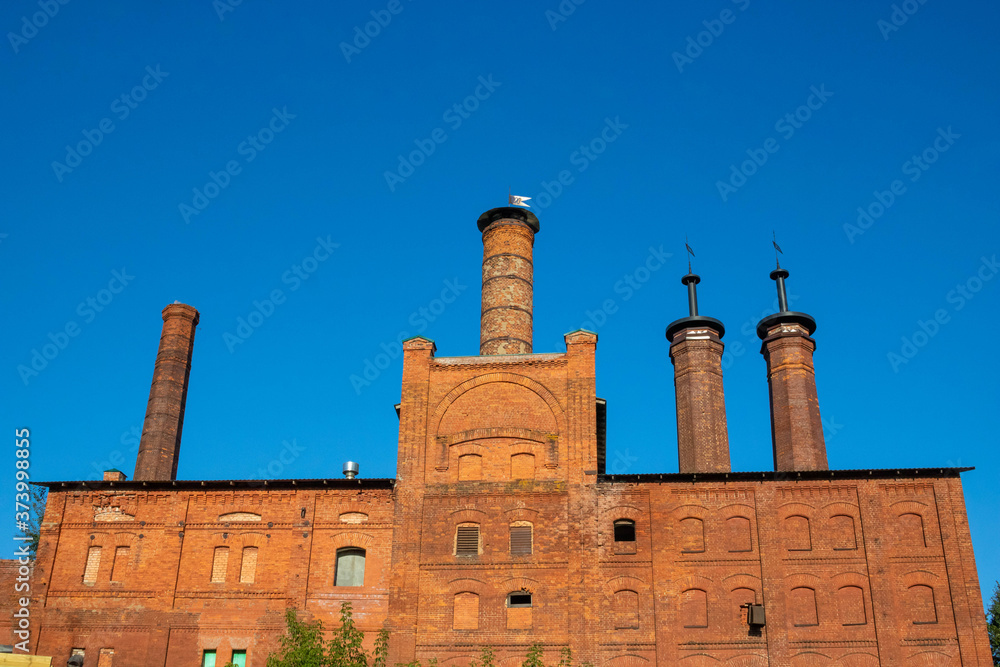 Factory brick chimneys on a red old building against a blue sky