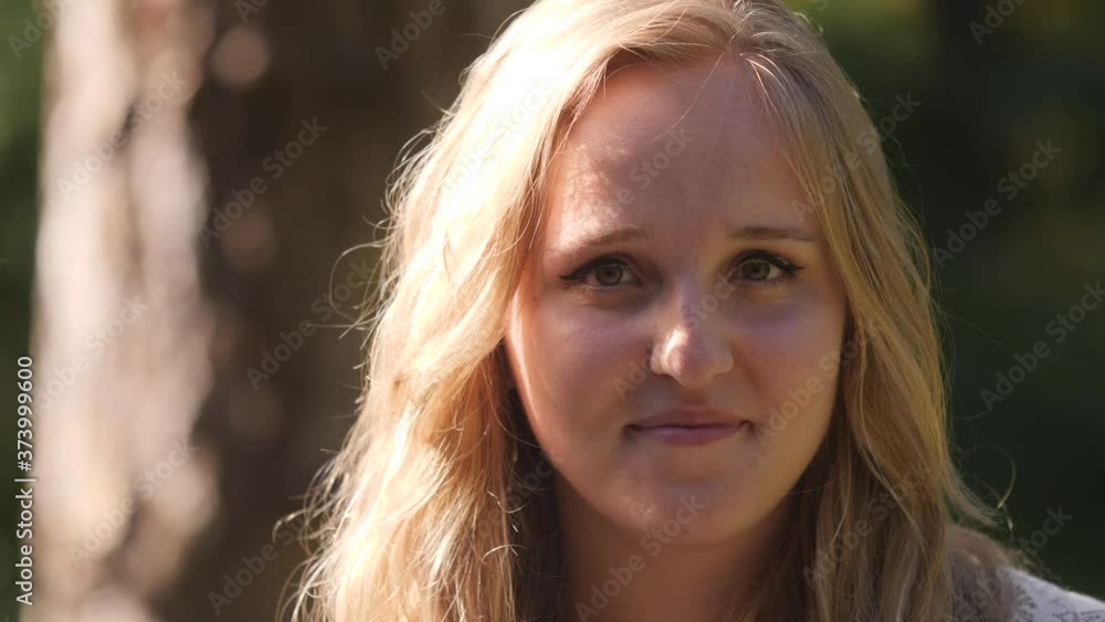 Beautiful young blond woman in white dress looks into camera in forest close-up Beautiful young blond woman in white dress looks into camera in forest close-up