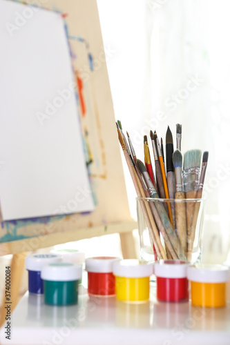 paints and brushes on the background of the easel