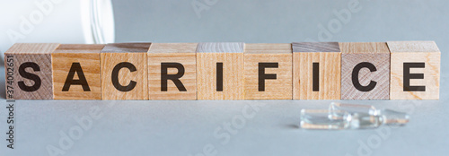 the word SACRIFICE written in wooden letters on a grey background