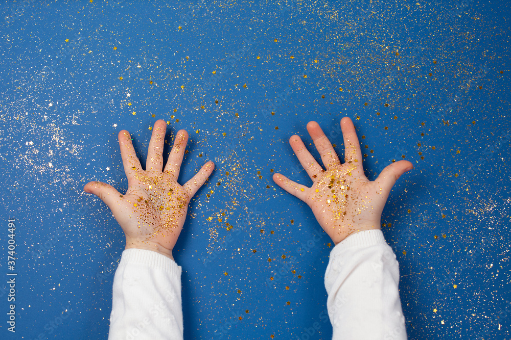 Child's hands holding golden stars on sparkling blue background. Child's hands holding golden stars on sparkling blue background.