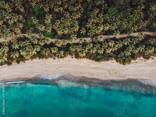 Aerial drone view of paradise beach and the road along it with palm trees and blue water of Atlantic Ocean at Esmeralda beach, Miches, Dominican Republic 