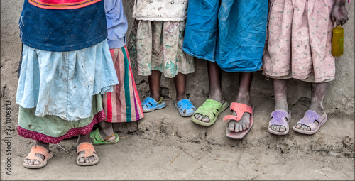 Young African children with flip flops on and colorful clothing