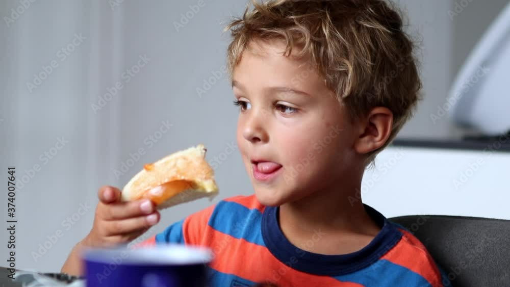 Candid little boy at morning breakfast table eating bread with jelly Candid little boy at morning breakfast table eating bread with jelly
