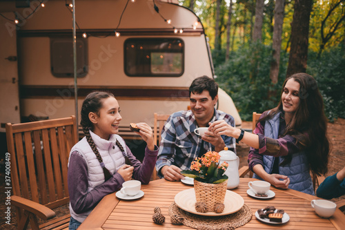 Happy family on a camping trip relaxing in the autumn forest. Camper trailer. Fall season outdoors trip