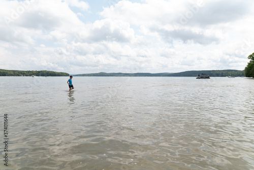 Boy walking in turquoise water on Walloon Lake in Michigan