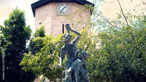 A statue with a clock tower in the background timelapse