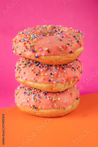 Pink donut with sprinkles on a orange and purple backgroud