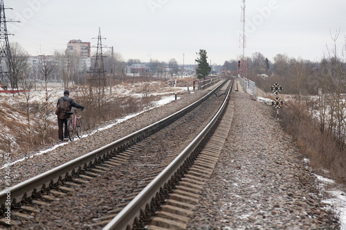 A man with a bicycle walks along the railway photo