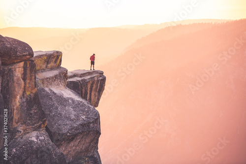 A male hiker stands at the edge of a cliff at Taft Point, Yosemite National Park, California photo