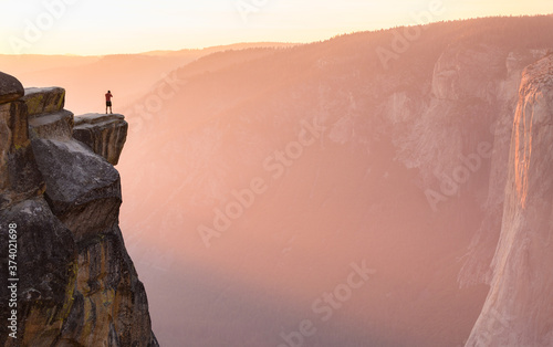 A male hiker stands at the edge of a cliff at Taft Point overlooking El Capitan in Yosemite National Park, California