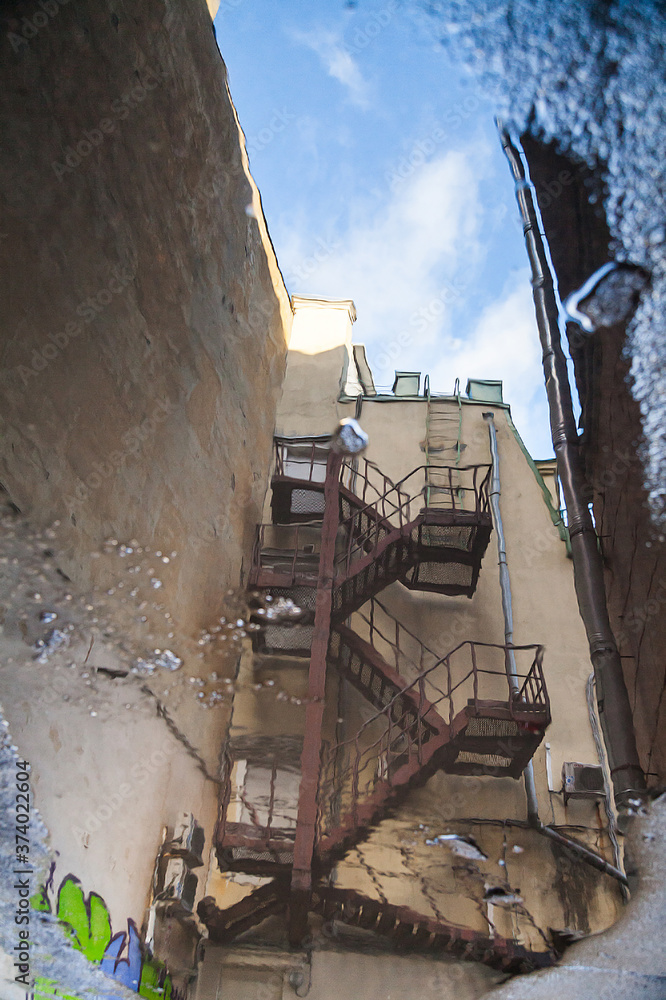 Fire escape in a residential building reflected in a puddle Fire escape in a residential building reflected in a puddle