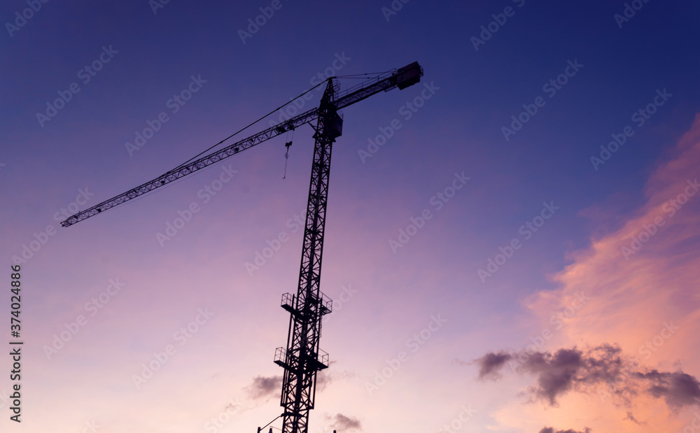 A high construction crane in colorful sunset A high construction crane in colorful sunset