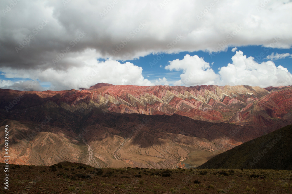 View of the colorful mountain, valley and meadow under a dramatic sky in Hornocal, Jujuy, Argentina. Beautiful rocky texture. 