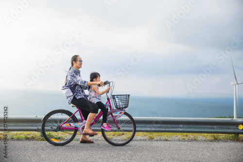 Grandmother with granddaughter in park.  Little Asian girl and grandmother riding on bicycle with great fun. family, leisure and people concept.