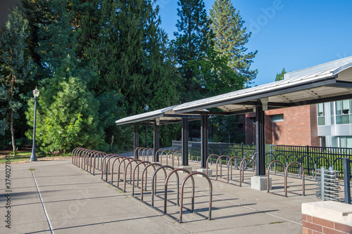 Empty bike racks on a bright, sunny public university campus highlight the absence of students.