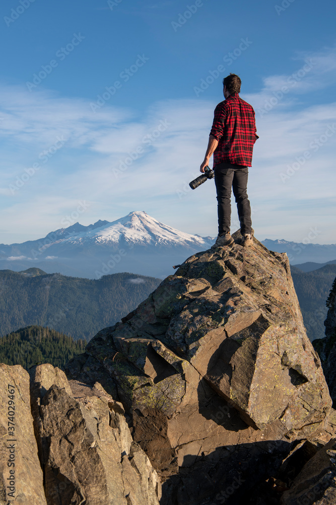 Obraz premium Man Standing On Cliff With Camera In The Pacific Northwest 