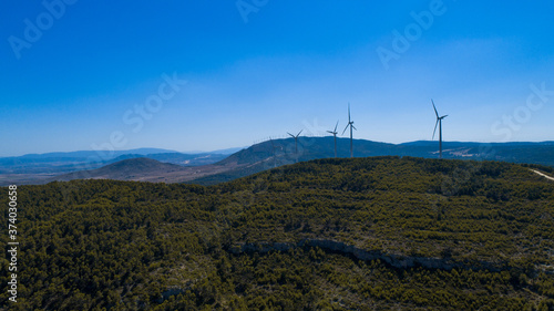 Aerial view of Wind Generating stations at big first mountains on a background of blue sky. Spain