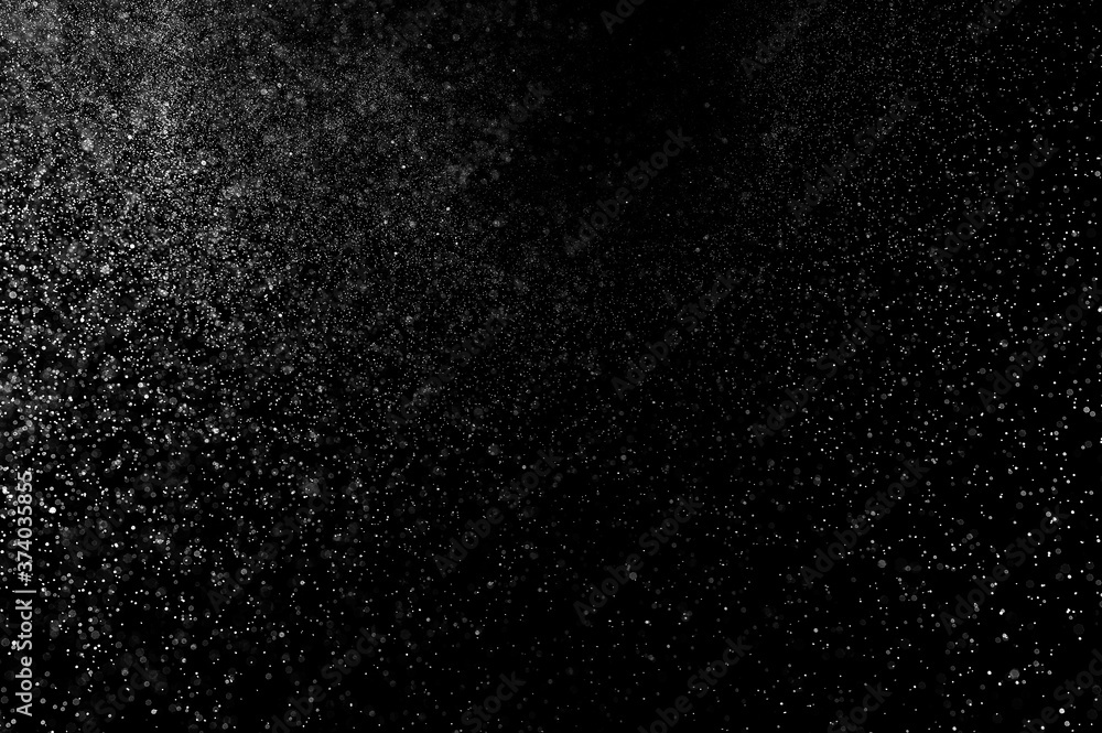 Abstract splashes of water on black background. Freeze motion of white particles. Rain, snow overlay texture.