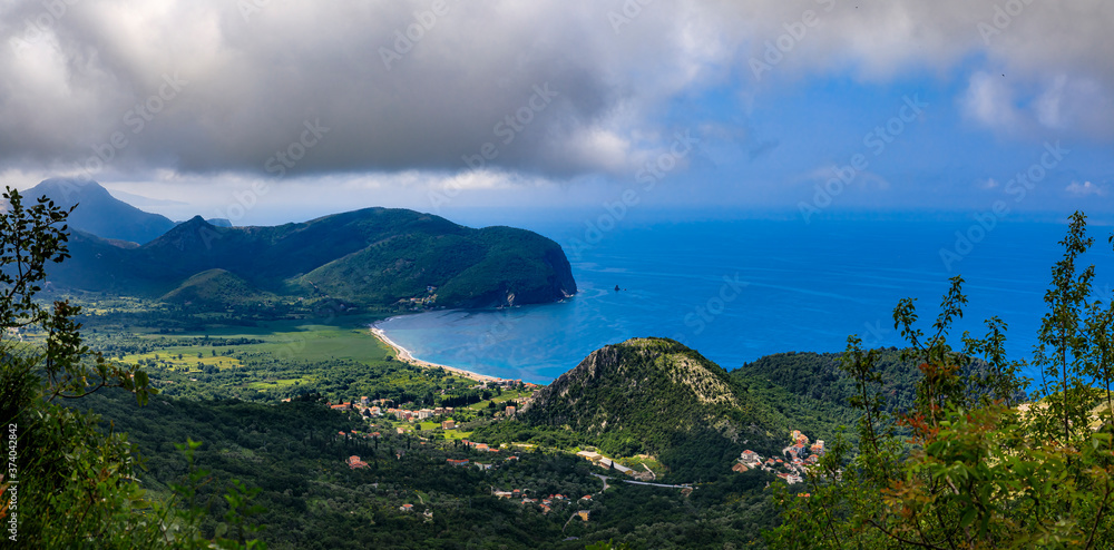 Panorama of Adriatic Sea coastline with mountains and low hanging clouds near Petrovac in Budva Riviera, Montenegro