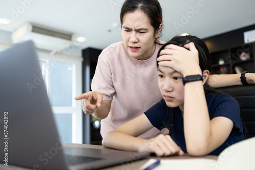 Foto Angry mother scolding her daughter about an education on computer,stressed stude