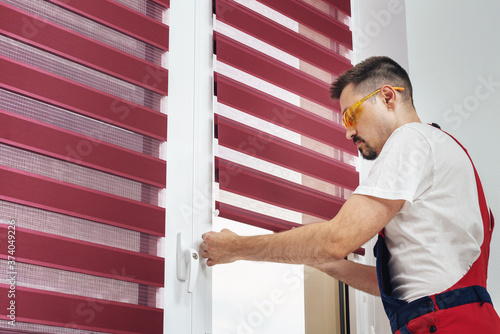 Construction worker man in a uniform installing new window blinds