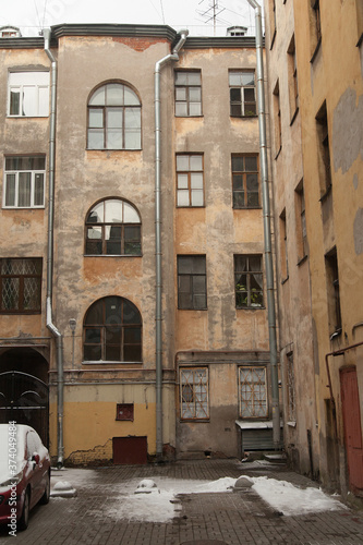 Fototapeta Naklejka Na Ścianę i Meble -  The courtyard of an old apartment building in St. Petersburg with yellow shabby walls