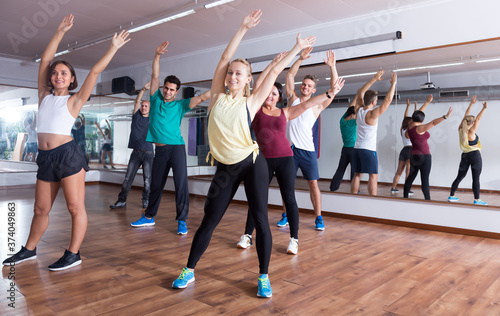 Laughing positive people learning zumba steps in dance hall