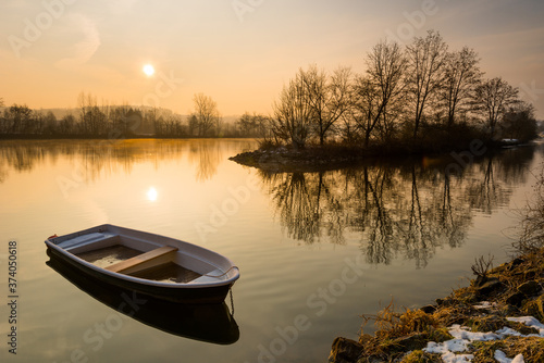 Broken rowboat anchored on riverbank on cold winter morning