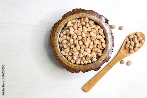 Uncooked dried Chickpeas in a wooden bowl on white background. Preparation for making a hummus dish.High protein ingredient with copy space.  