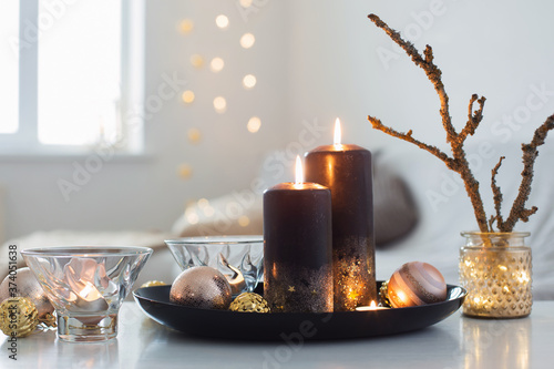 black burning candles with Christmas balls in white interior