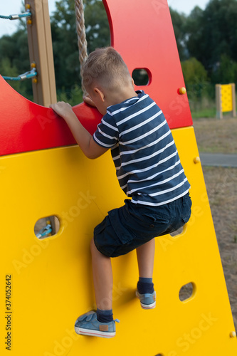 A boy climbs the wall in the Playground. rock climbing classes. Children's outdoor games