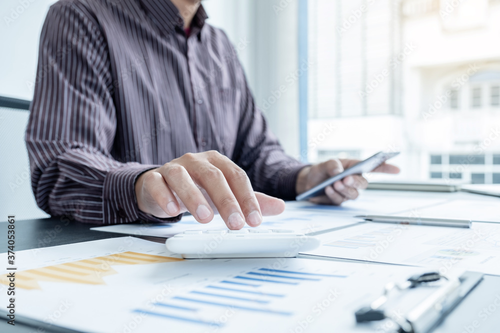 The hands of a male businessman are analyzing and calculating the annual income and expenses in a financial graph that shows results To summarize balances overall in office The hands of a male businessman are analyzing and calculating the annual income and expenses in a financial graph that shows results To summarize balances overall in office