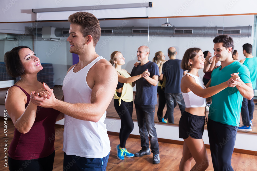 Cheerful dancing couples learning salsa at dance class