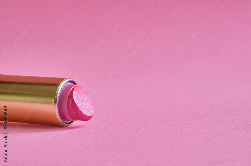 An old used tube of lipstick lies on pink background An old used tube of lipstick lies on pink background