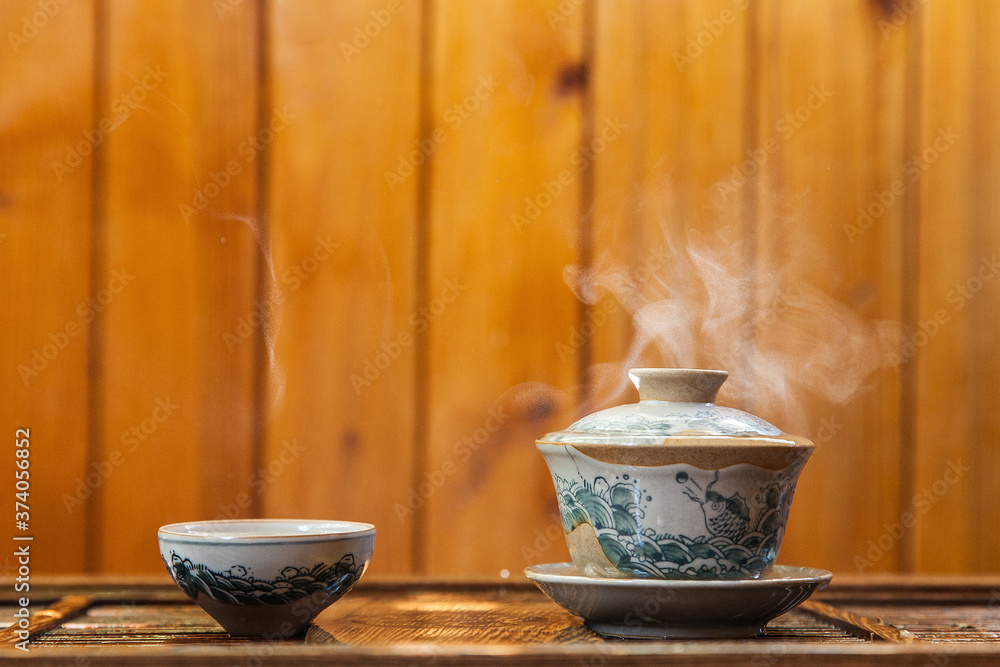 Cup of chinese tea with cloud of steam on wooden background Cup of chinese tea with cloud of steam on wooden background