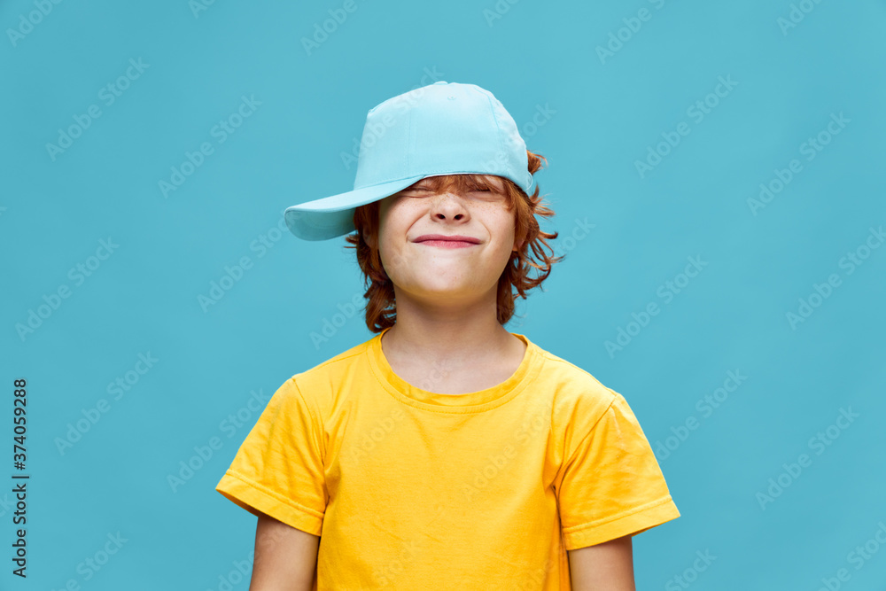 A boy with red hair with narrowed eyes and a cap on his head A boy with red hair with narrowed eyes and a cap on his head