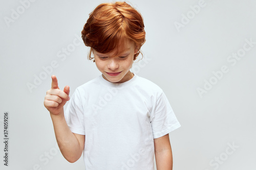 Wallpaper Mural Red-haired boy looks down and shows his index finger up Copy space Torontodigital.ca