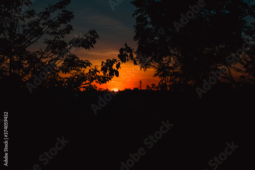 Pôr do sol no horizonte com sombras de árvores e degradê de cores no céu © XM4THX