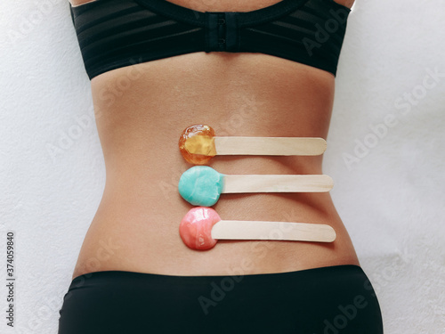 Top view on sticks with hot wax and sugar paste for depilation hair removal procedure on female back. The concept of depilation, epilation, waxing, shugaring.