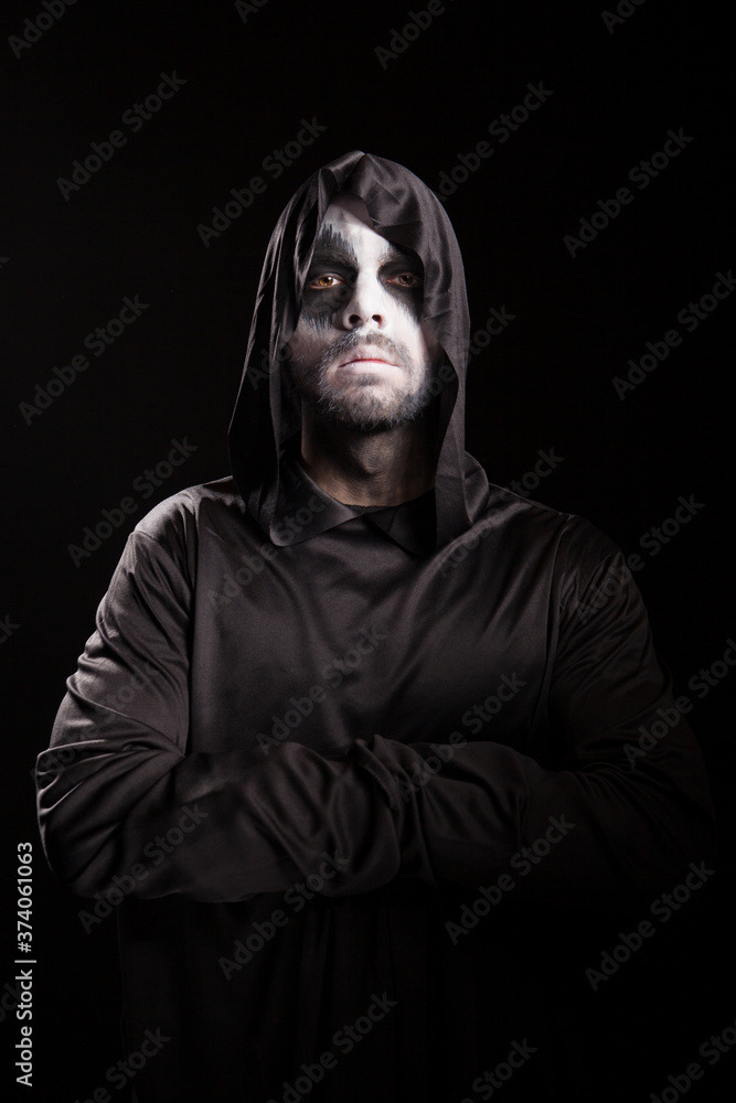 Portrait of grim reaper with hands crossed isolated over black background. Halloween costume.