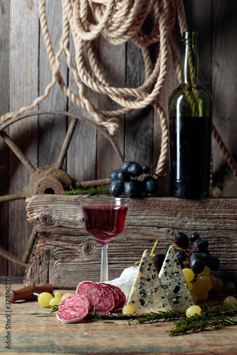 Rustic still life with red wine and snacks.