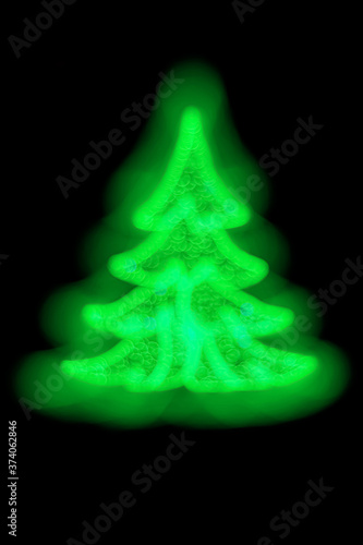 New Year tree on a black background made of garlands of green color. An original decoration idea for Christmas or New Year. Festive blurred defocused background