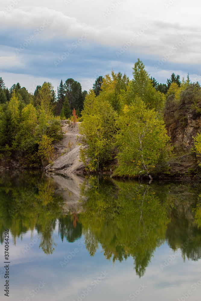 Stunning photo of fall foliage reflected on a lake with a glass like mirror water surface Stunning photo of fall foliage reflected on a lake with a glass like mirror water surface