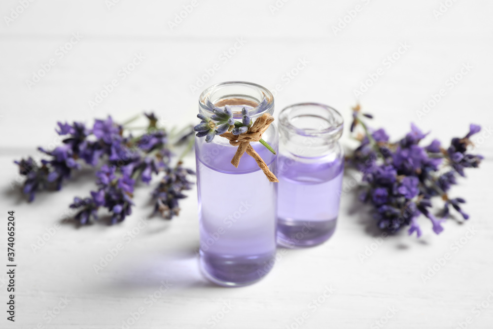 Bottles of essential oil and lavender flowers on white wooden table Bottles of essential oil and lavender flowers on white wooden table