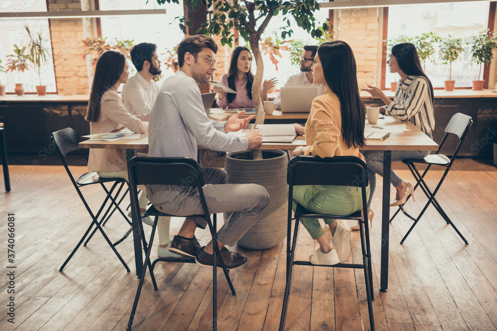 Fototapeta premium Photo of business people colleagues sit around table members share successful anti crisis crash plan ideas team professionals discuss graphics charts 2020 pre budget numbers office indoors